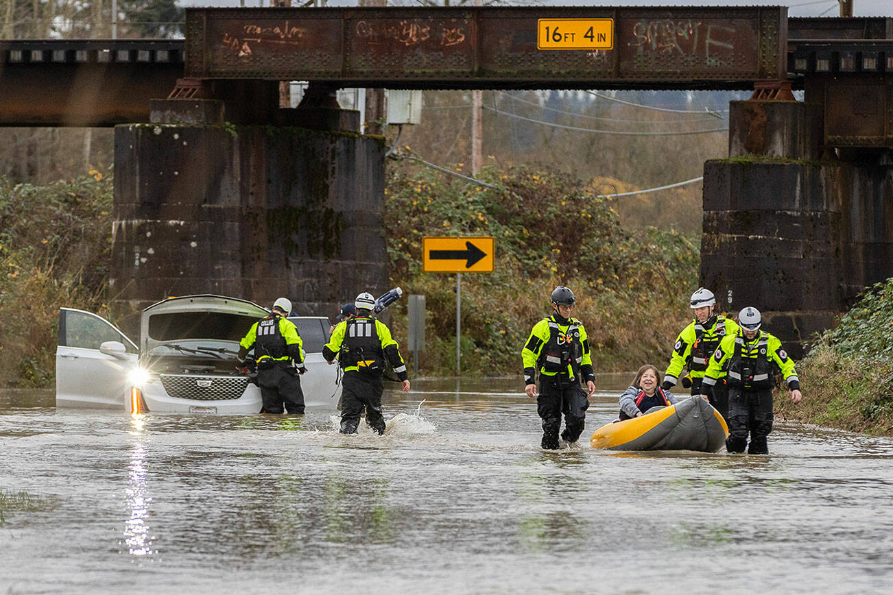 Snohomish Regional Fire & Rescue and Snohomish County Fire District 4 water units use an inflatable kayak to rescue occupants of a car stuck in floodwater covering a portion of Old Snohomish Monroe Road on Tuesday, Dec. 9, 2025 in Snohomish, Washington. (Olivia Vanni / The Herald)