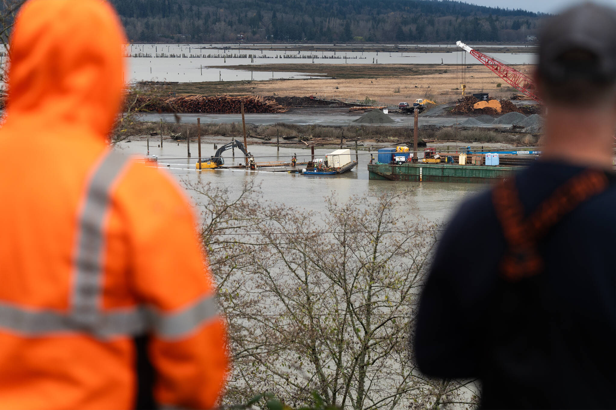 Onlookers watch as crews work while a barge sinks below water near Port Gardner Bay on Wednesday, Dec. 10 in Everett, Washington. (Will Geschke / The Herald)