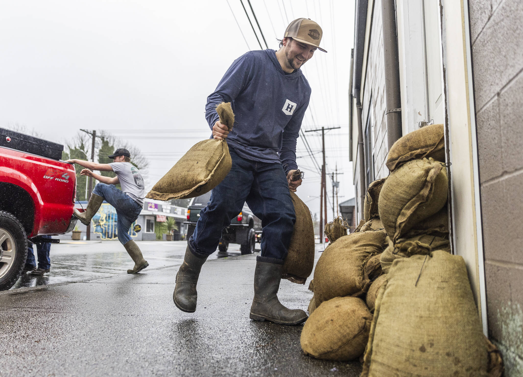 Zach Day sandbags the entrance to his grandparents residence along Main Street on Wednesday, Dec. 10, 2025 in Sultan, Washington. (Olivia Vanni / The Herald)