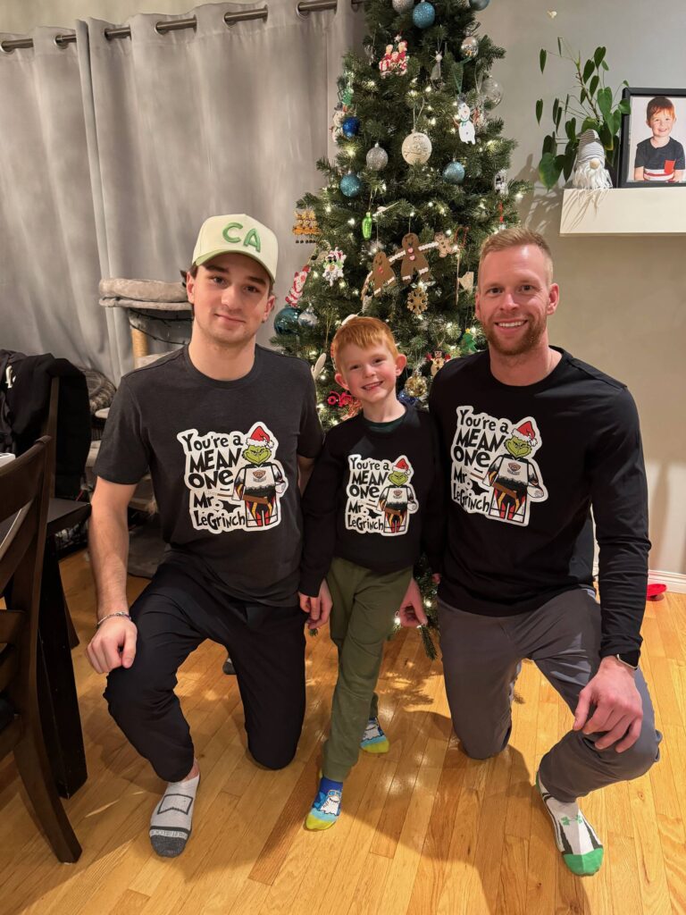 Silvertips goalie Raiden LeGall (left), his hometown goalie coach Tim Morison (right) and Morison&rsquo;s son, Mavryck (center), pose in front of a Christmas tree wearing their custom &lsquo;LeGrinch&rsquo; shirts. (Photo courtesy of Tim Morison)
