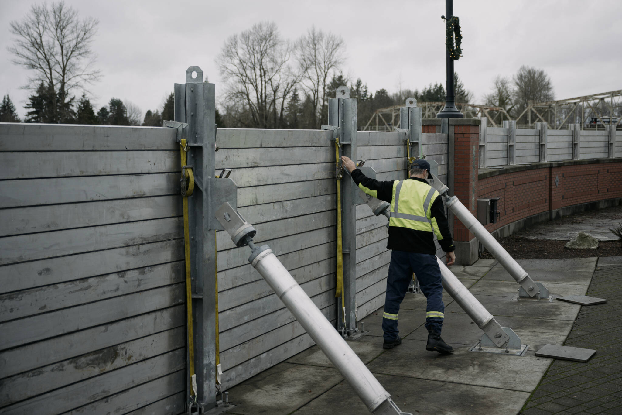 Jsason Phipps of the City of Mount Vernon tightens straps on the flood wall along the Skagit River in downtown Mount Vernon on Thursday. The river is forecast to crest on Friday morning after several days of heavy rain pushed waterways in the region to record levels. (Grant Hindsley/The New York Times)