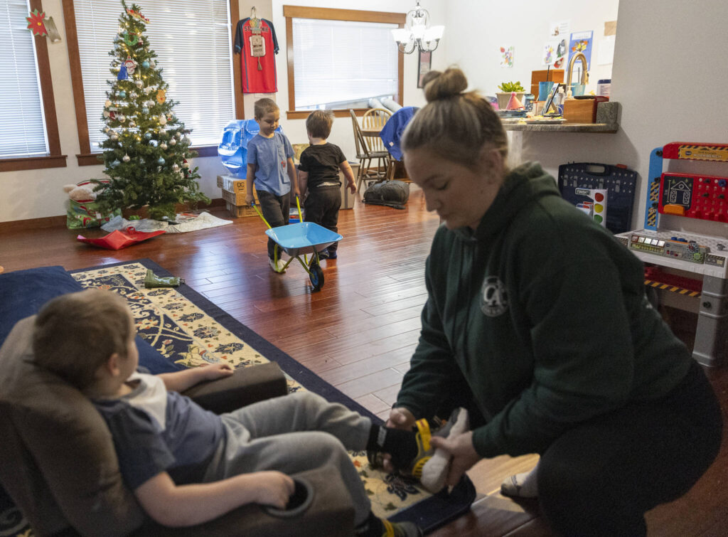 Declan, 5, and Oaklen, 2, play while Boyle puts shoes on Raiden, 4, as she gets her three sons ready to leave for daycare on Tuesday, Dec. 30, 2025 in Marysville, Washington. (Olivia Vanni / The Herald)
