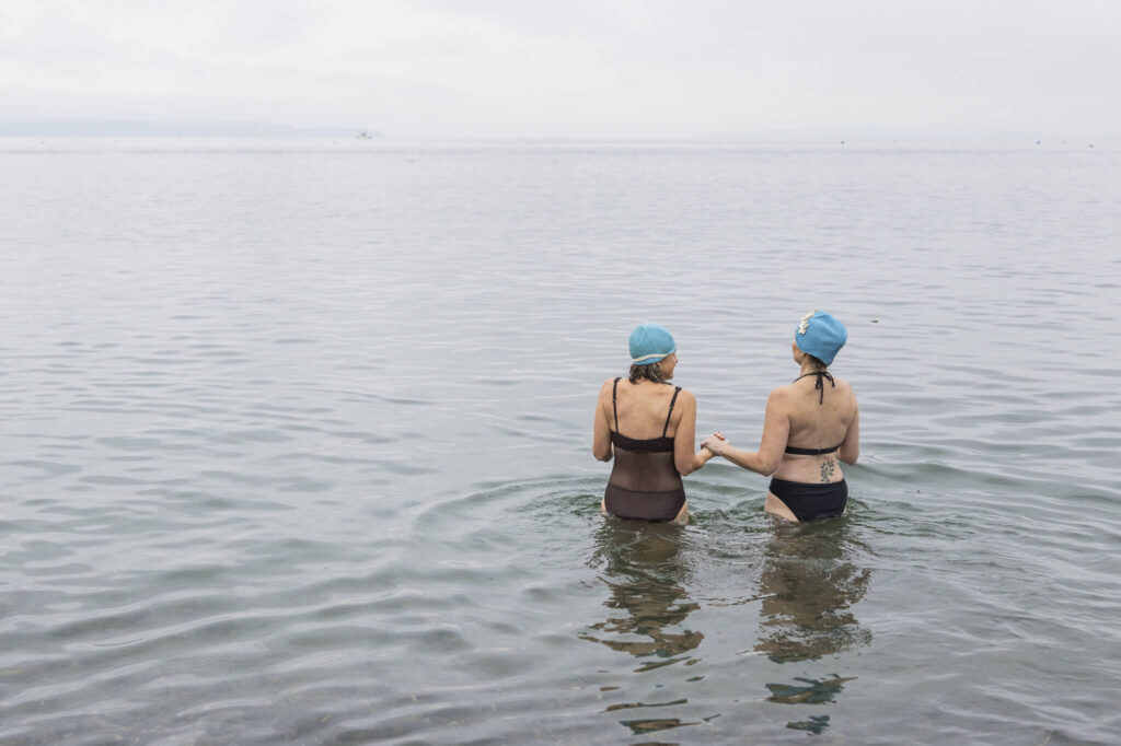 People in matching swim caps hold hands as they walk into the water at Brackett&rsquo;s Landing North during the 19th annual Polar Bear Plunge on Thursday, Jan. 1, 2026 in Edmonds, Washington. (Olivia Vanni / The Herald)
