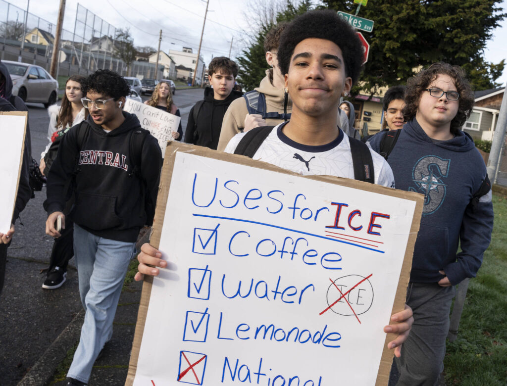 Tyree Elegan, a sophomore at Everett High School, holds a sign and walks along 25th Street during a walkout at the school in protest of ICE on Tuesday, Jan. 13, 2026, in Everett, Washington. (Will Geschke / The Herald)
