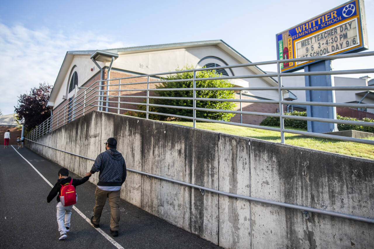 A parent walks a child to class at Whittier Elementary on the first day of school in September 2023 in Everett. Whittier, as with almost all schools in the district, would see upgrades to safety and security, building systems, technology and site improvements if voters pass a bond request in the Feb. 10 special election. (Olivia Vanni / The Herald file photo)