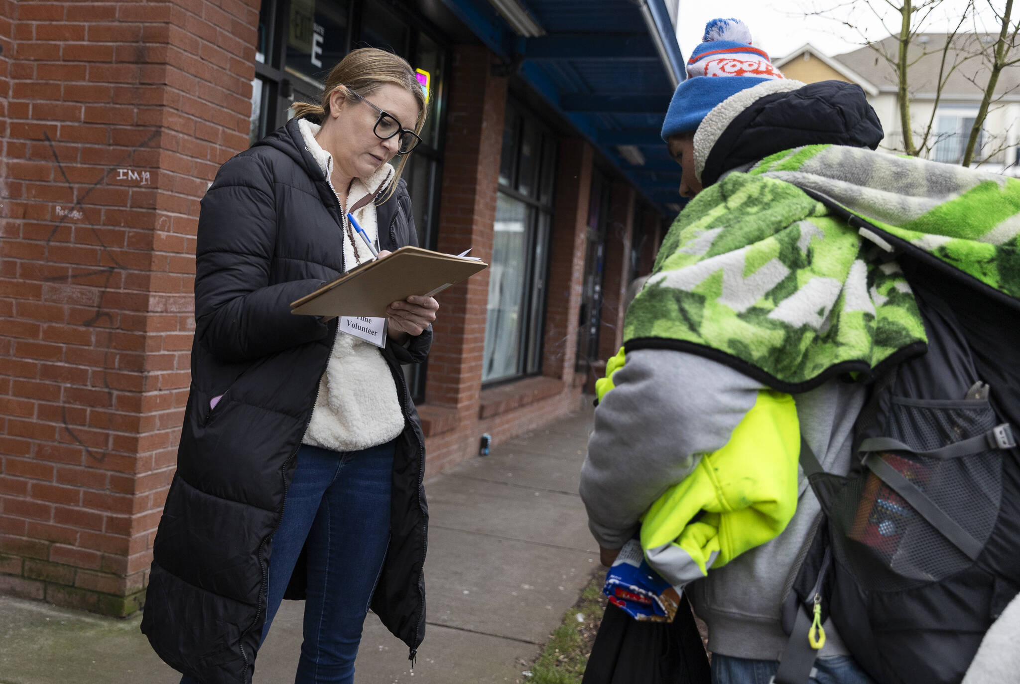 Toni Gardner, a volunteer with the Point In Time count, asks an individual PIT survey questions outside of the Dkj Foodmart on Tuesday, Jan. 27, 2026, in Everett, Washington. (Olivia Vanni / The Herald)