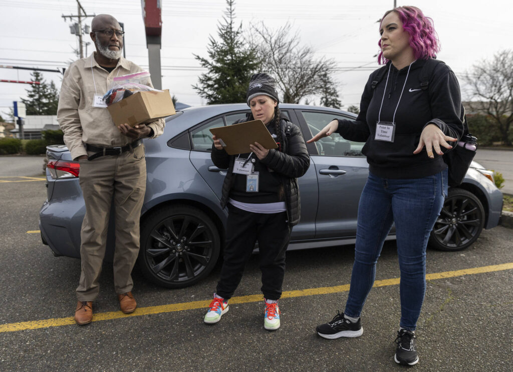 Jobe Momodouon, Rachel McGee and Amanda Amoruso talk before heading out for their Point In Time count shift on Tuesday, Jan. 27, 2026, in Everett, Washington. (Olivia Vanni / The Herald)
