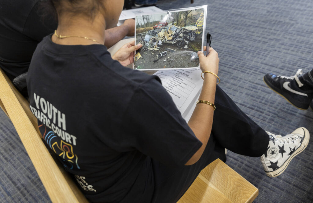 A photograph of an example of a speed-induced crash is passed around to Youth Traffic Court participants at the Snohomish County Courthouse on Friday, Jan. 30, 2026 in Everett, Washington. (Olivia Vanni / The Herald)
