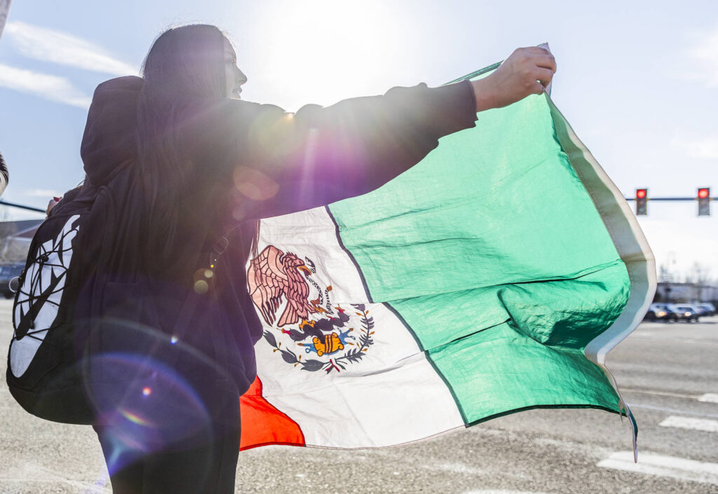 Jazmine Bustos, a sophomore at Lakewood High School, waves a Mexican flag during a student walkout and protest on Thursday, Feb. 5, 2026 in Marysville, Washington. (Olivia Vanni / The Herald)
