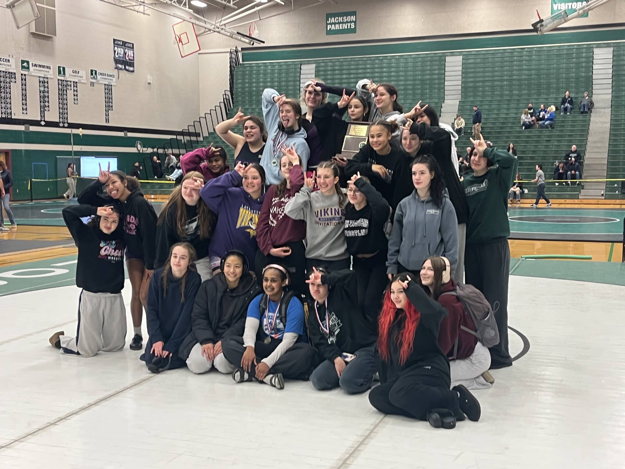 Lake Stevens girls wrestling poses with the District 1 4A Championship trophy on the podium at Jackson High School on Feb. 6, 2026. (Joe Pohoryles/The Herald)