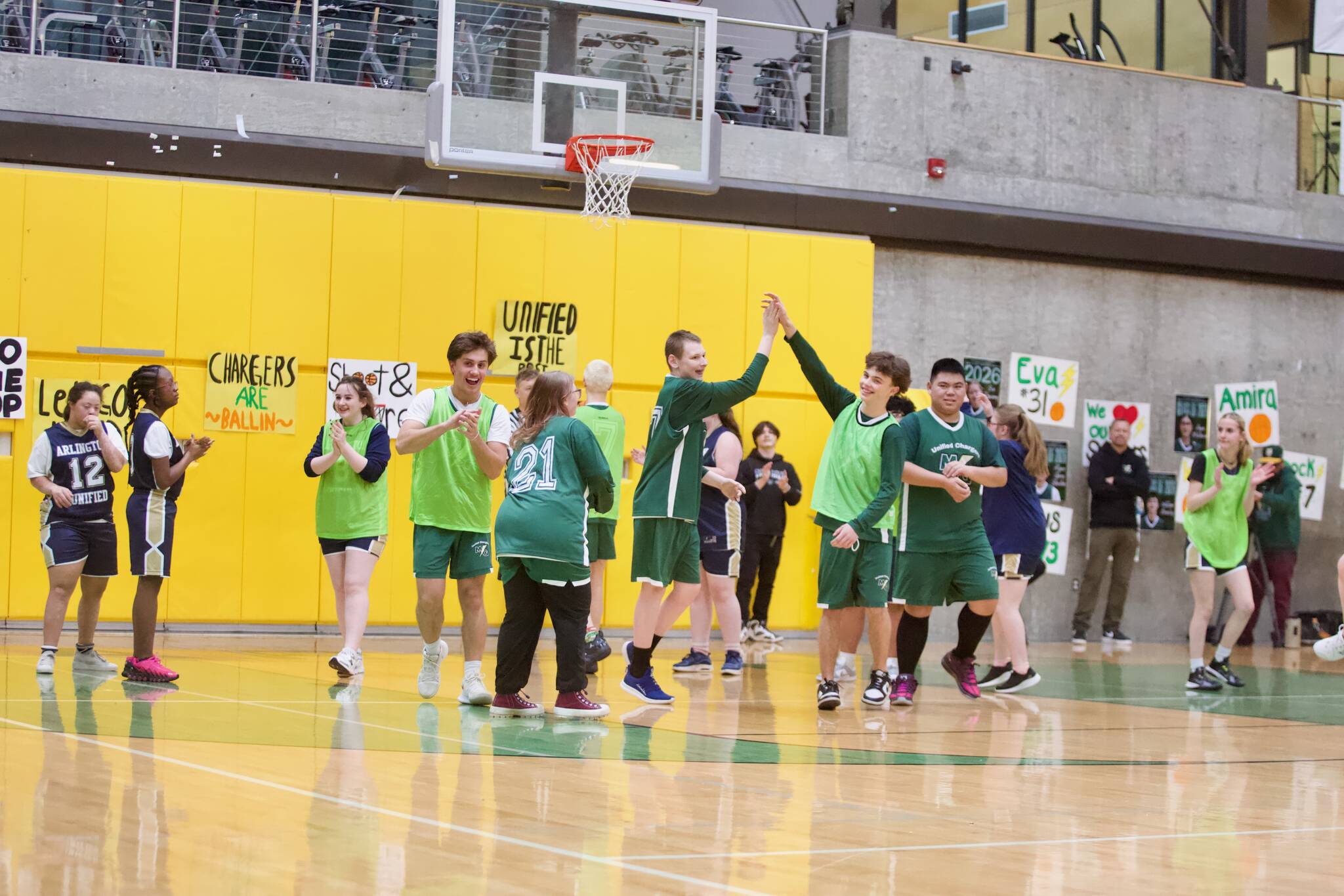 Surrounded by applauding teammates and opponents, Marysville Getchells Carson Ringen high-fives partner athlete William Brierley after making a shot during the Chargers unified basketball game against Arlington at Marysville Getchell High School on Feb 9, 2026. (Joe Pohoryles/The Herald)