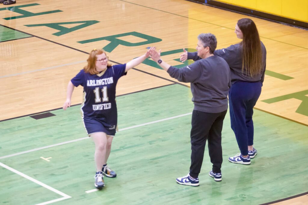 Arlington&rsquo;s Keiley Hatfield (11) high-fives her coaches Necole Yon-Wagner (left) and Maicee Delaney during the pregame introductions for the Eagles unified basketball game at Marysville Getchell High School on Feb. 9, 2026. (Joe Pohoryles/The Herald)
