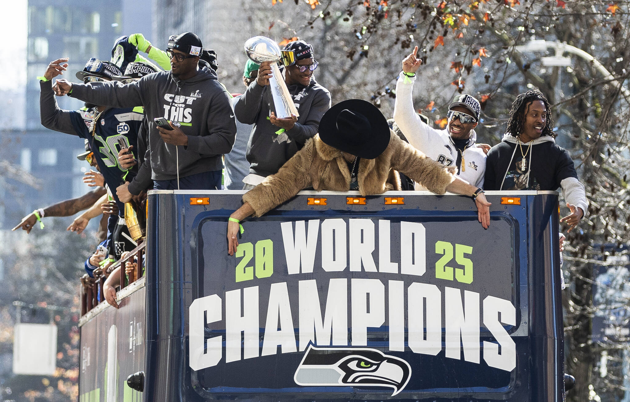 Seattle Seahawks Kenneth Walker III holds the Lombardi Trophy and other players cheer as one of their buses makes its way up 4th Avenue during their World Champions Parade on Wednesday, Feb. 11, 2026, in Seattle, Washington. (Olivia Vanni / The Herald)