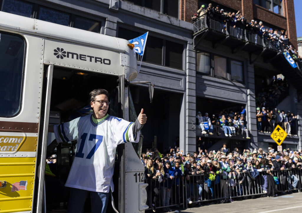 Washington Gov. Bob Ferguson waves at fans from a bus along 4th Avenue during the Seahawks World Champions Parade on Wednesday, Feb. 11, 2026, in Seattle, Washington. (Olivia Vanni / The Herald)
