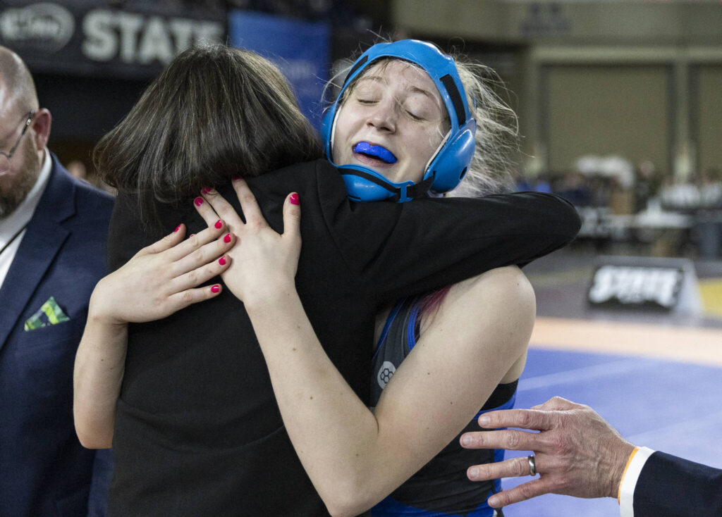 Shorewood&rsquo;s Finley Houck hugs one of her coaches after winning the 3A girls 115-pound championship match at the Mat Classic on Friday, Feb. 20, 2026 in Tacoma, Washington. (Olivia Vanni / The Herald) 
