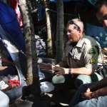 Snohomish County sheriff's Sgt. Ian Huri speaks with Rochelle Hammond at a homeless encampment in Everett in August. Sgt. Huri and social worker Jesse Calliham had been working with Hammond and other residents to get them connected with social services. (Genna Martin / The Herald)