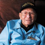 Pearl Harbor Survivor Walter Bailey who passed away May 27, is seen here in his favorite chair, behind the family couch, happily watches the Dr. Oz show on a big screen and, as usual, wearing his Pearl Harbor Survivor cap. The photo was taken December 4, 2013. (Dan Bates / The Herald)