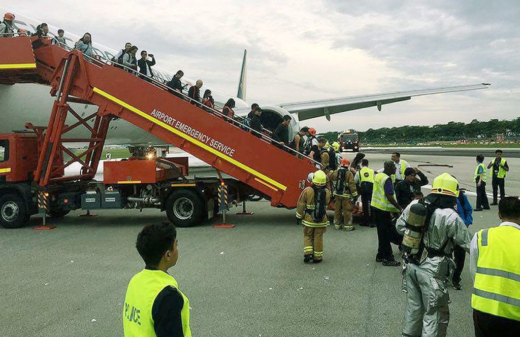 This image provided by Lee Bee Yee shows passengers disembarking a Singapore Airlines flight after an engine fire, at Changi International Airport in Singapore on Monday. A Singapore Airlines statement said the Boeing 777-300ER was on its way to Milan when it turned back &ldquo;following an engine oil warning message.&rdquo; (Lee Bee Yee via AP) MANDATORY CREDIT