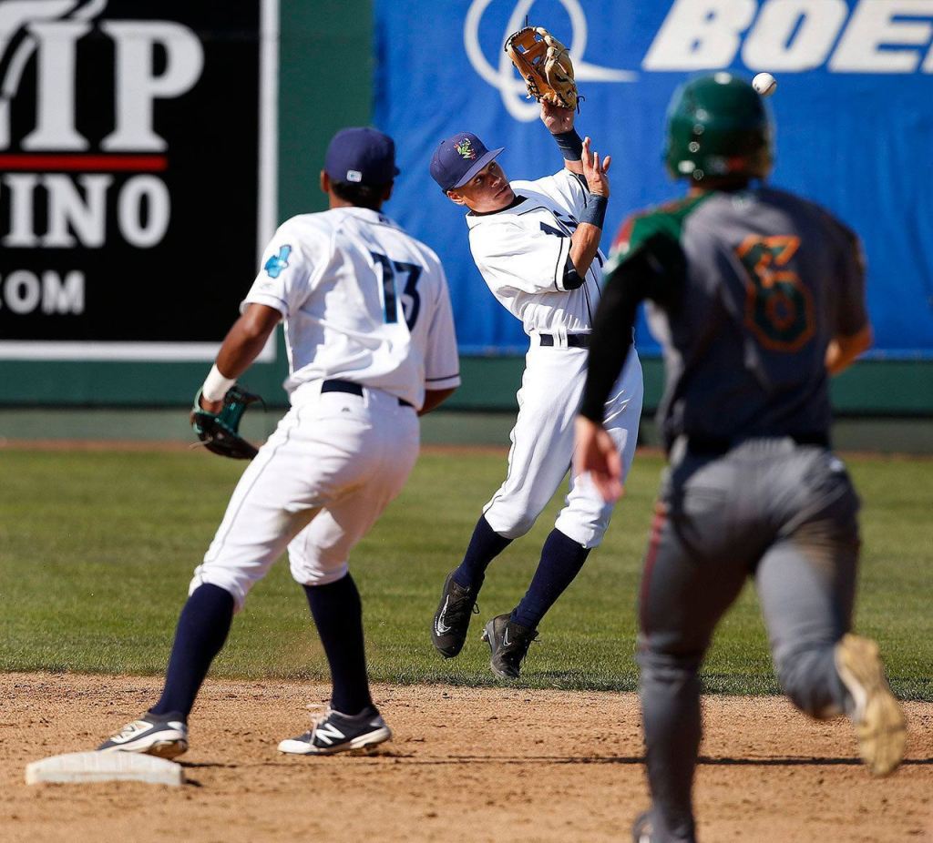 Aquasox shortstop Bryson Brigman (center) bobbles a groundball during Sunday&rsquo;s game against the Boise Hawks. (Ian Terry / The Herald)