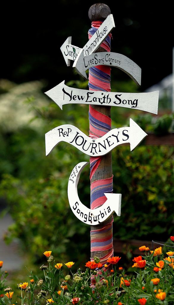 A colorful signpost with directions occupies a corner where pathways cross. (Dan Bates/The Herald)