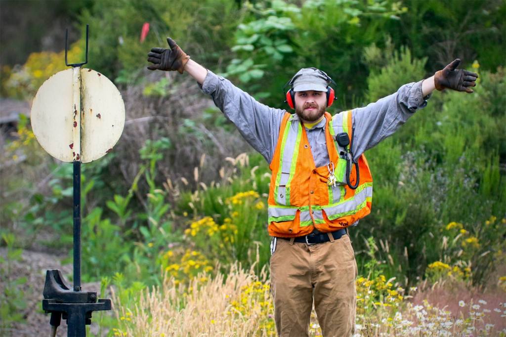 Nathan Proudfoot, conductor, signals to the engineer, Les Crowder, during a weekly run from Woodinville to Snohomish on July 7. (Kevin Clark / The Herald)