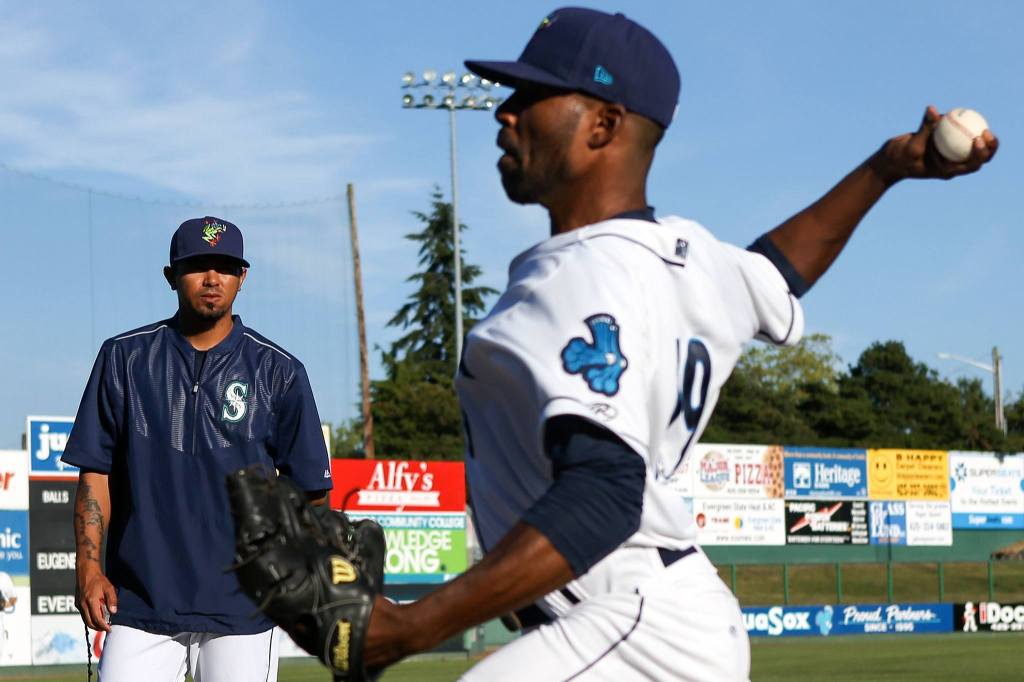 AquaSox pitching coach Moises Hernandez, the older brother of Mariners ace Felix Hernandez, looks on as Reggie McClain warms up before a game against the EmeraldsWednesday at Everett Memorial Stadium. (Kevin Clark / The Herald)