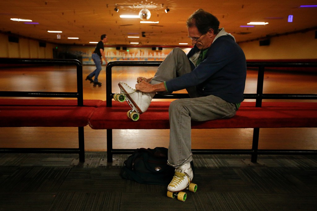 John Walker, of Seattle, laces up his skates before taking to the floor at a public session at Lynnwood Bowl and Skate on Thursday. Walker has been skating at the rink since 1964. (Ian Terry / The Herald)