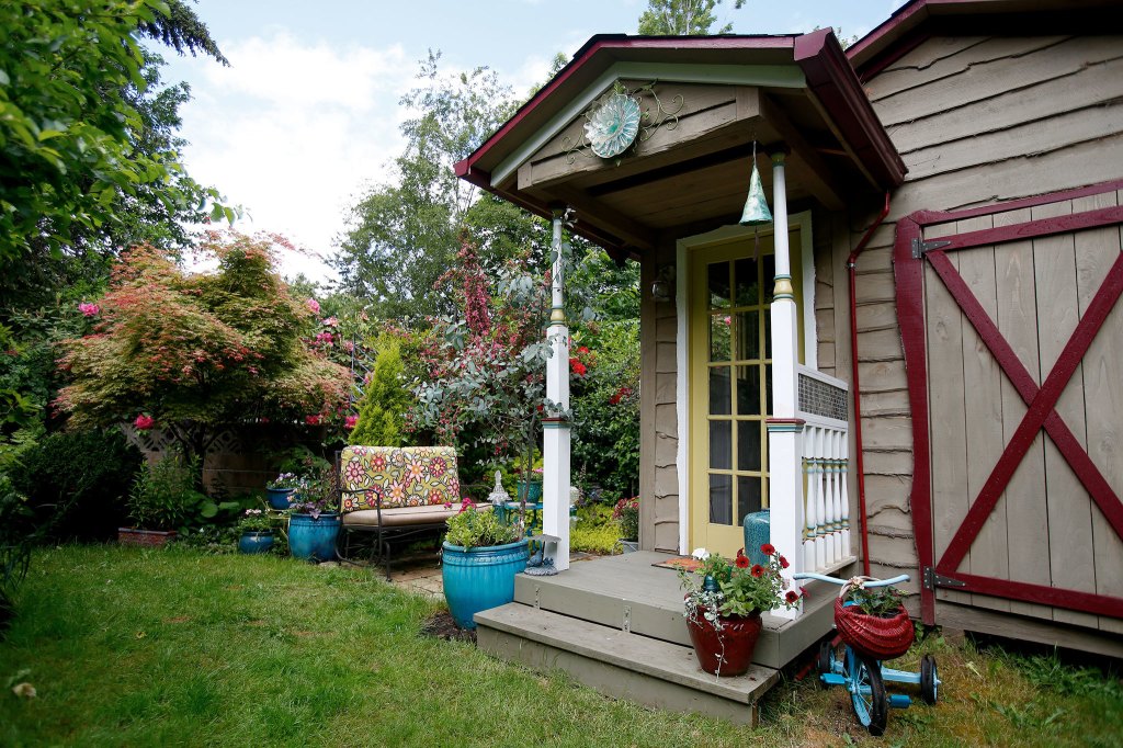 Andy Bronson / The Herald                                A garden shed at the home of John and Kathleen Neal on Friday, May. 20, 2016 in Montlake Terrace, Wa. The Neals are members with Northwest Perennial Alliance, which allow members to tour their garden. Shed built in 2012, built by Dan of Lacey (I&rsquo;ll get you his company name.. he should have credit), and enhanced by John. The man side, has double &lsquo;garage&rsquo; doors for John&rsquo;s small tractor and riding mower. The porch side is the cute &lsquo;she&rsquo; side. The railing and posts were created from recycled materials.