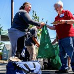 At Project Homeless Connect in Everett on Thursday, Jessica Riley hands laundry over to volunteer Del Saindon to wash in a portable laundromat. The last three months, Riley has been living with her daughter and daughter&rsquo;s boyfriend in a 1983 Volvo. (Dan Bates / The Herald)