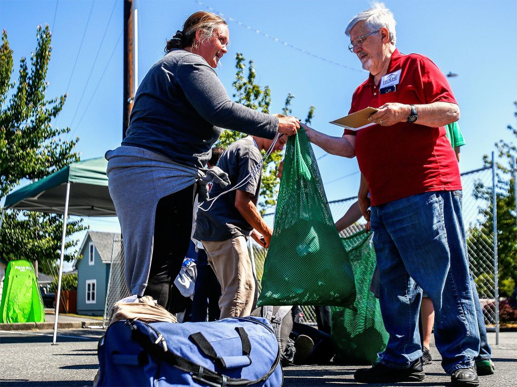 At Project Homeless Connect in Everett on Thursday, Jessica Riley hands laundry over to volunteer Del Saindon to wash in a portable laundromat. The last three months, Riley has been living with her daughter and daughter&rsquo;s boyfriend in a 1983 Volvo. (Dan Bates / The Herald)