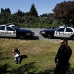 A young heroin addict waits in the grass near 128th Street Southwest as Snohomish County social worker Jesse Calliham (right) stays on the line waiting for confirmation that she would have a hotel room to stay in on June 29. After being on hold for 27 minutes, Calliham was finally able to secure a room for her which allowed for an easier transition into treatment. (Ian Terry / The Herald)