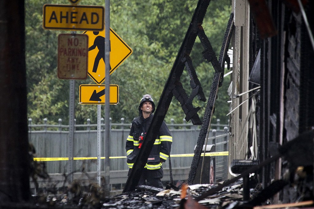 A firefighter surveys damage along 101st Avenue Northeast in downtown Bothell from a fire that broke out early Friday morning at the historical Mercantile Building on Main Street and spread to surrounding buildings. (Ian Terry / The Herald)