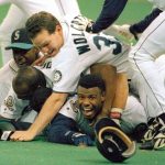 In this photo from Oct. 8, 1995, Seattle&rsquo;s Ken Griffey Jr. smiles from underneath a pile of teammates who mobbed him after he scored the winning run in the bottom of the 11th inning of Game 5 of a best-of-five playoff series against the New York Yankees. (AP Photo/Elaine Thompson, File)