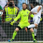 Sporting Kansas City forward Dom Dwyer (right) heads the ball into the net past Seattle Sounders goalkeeper Stefan Frei for a goal during the first half of Sunday&rsquo;s MLS game in Kansas City, Kan. (AP Photo/Orlin Wagner)