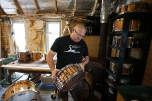 Mark Hanna examines a snare drum he and his his wife, Teresa, made at the couple&rsquo;s wood workshop on their property in Oso on Thursday. Three years ago, Mark and Teresa made their first drum. Today they own Sway Mechanika, a company that produces custom high-end drum sets from local wood that is often picked up from scrap piles.