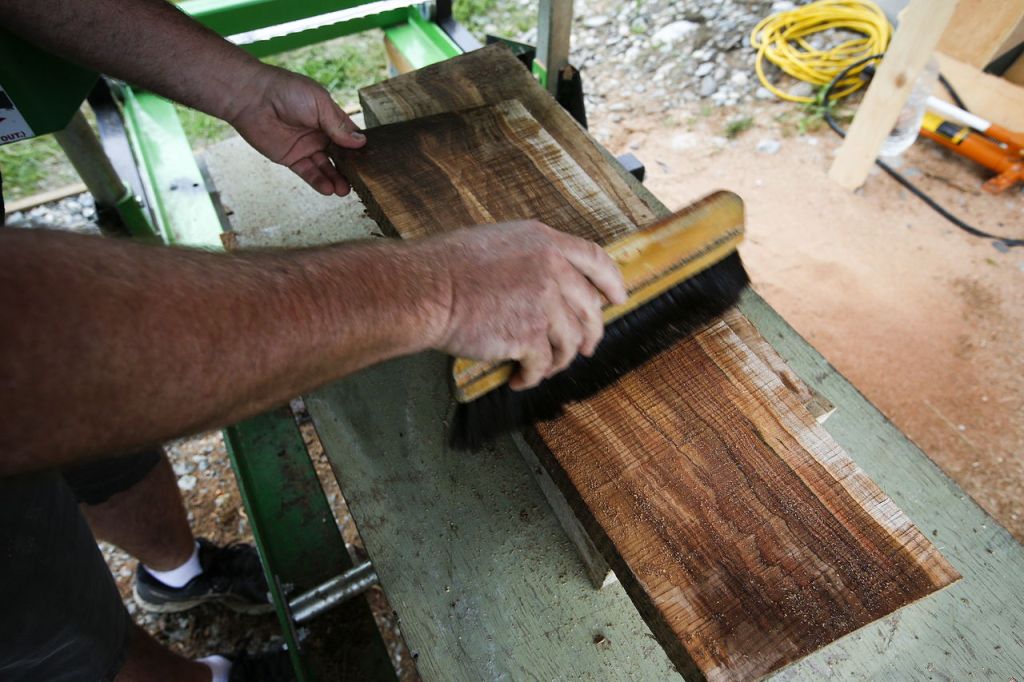 Mark Hanna brushes away sawdust to reveal an intricately patterned wood grain on a piece of quilted maple.