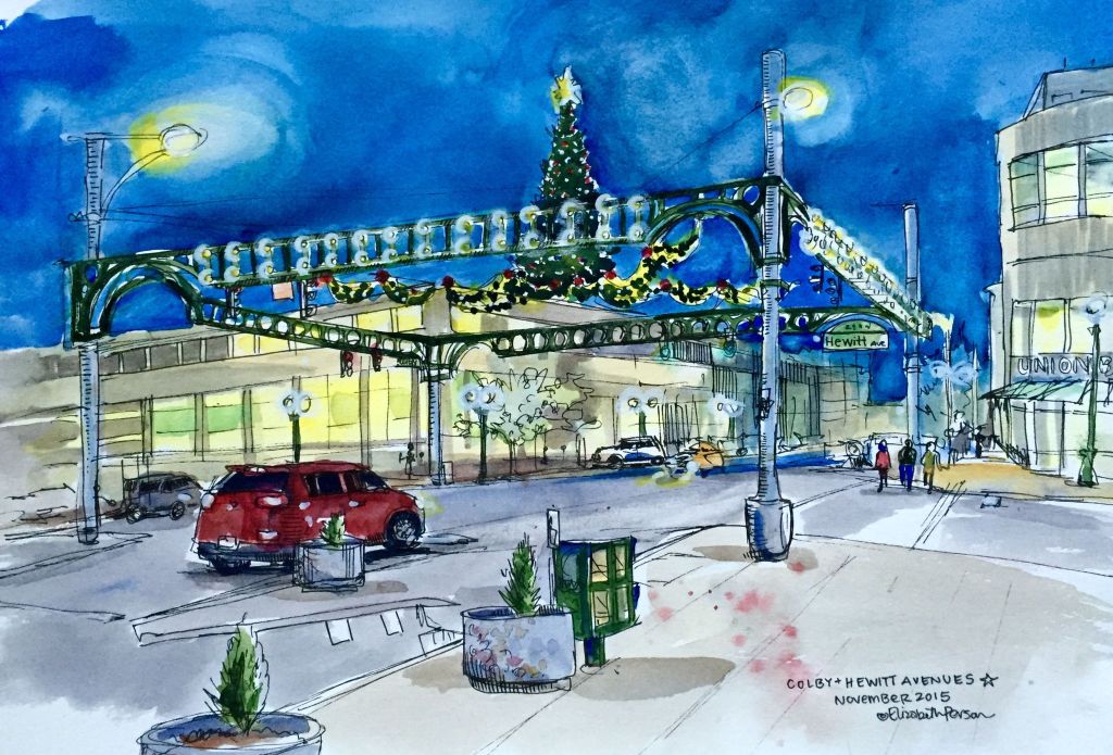 Artist statement: Every year, the intersection of Colby and Hewitt avenues magically transforms into a beacon of holiday cheer. I&rsquo;m never quite sure when the change will occur, so it has the same effect on me it&rsquo;s had since I was a kid &mdash; a moment of wonderment, of delight. What choice does one have after all, when there is a Christmas tree suspended overhead, but to surrender to the ostentatious joys of the season at hand?