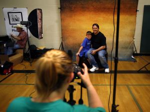 Volunteer Christy Neigel, of Sultan, takes a photo of Dave Norman and his 8-year-old son, Jerry, during last year&rsquo;s Project Homeless Connect. The annual event, providing resources for homeless and low-income people, will be held July 14 at Everett High School.