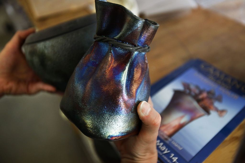 Goff picks up some raku pots, which are individually unique when they come out of the kiln.