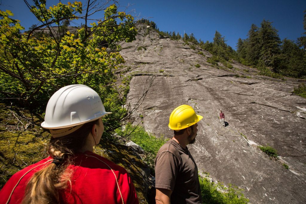 Tatiana Weaver and Bryan Hawkins watch as Chris Turvey climbs up 3 O&rsquo;Clock Rock during a Mountaineers work party to reconstruct the 8 Mile Trail near Darrington on June 4.
