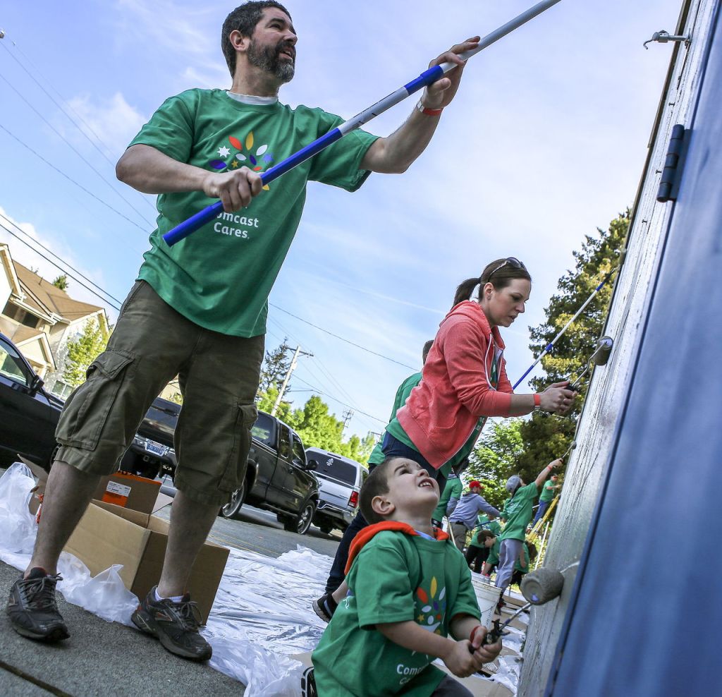 Curtis Plumb (left) Christie Plumb and Caleb Plumb, 4, paint Saturday morning at the Marysville Boys & Girls Club. More than 250 local Comcast employees volunteered their day to paint, clean, landscape, organize and repair the center that hosts more than 800 kids a year.