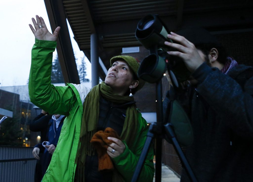 Ursula Valdez, a University of Washington Bothell interdisciplinary arts and sciences lecturer, guides a student using a spotting scope to view crows coming in to roost.
