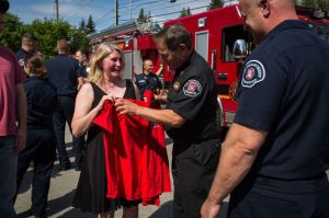 Brenda Welch receives an honorary fire department shirt Friday from Assistant Chief Greg Sieloff at Lynnwood Fire Station No. 15. Welch reunited with the firefighters and medics who saved her life after she was found unconscious and burned inside her ex-husband&rsquo;s garage two years ago.