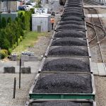 A train hauling coal to British Columbia heads north out of Seattle between office buildings, condos and the downtown waterfront.