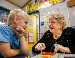 At Allen Creek Elementary School in Marysville, retired teacher Carol Albright enjoys a lighter moment while working with first-grader Landen Resch on math. After two decades of teaching, Albright helps out three times a week at the school.