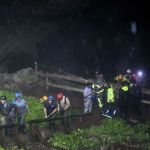 Rescued people walk out of the entrance to Hidden River Cave on Thursday.