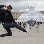 Street artist JR poses in front of the Louvre Pyramid in Paris on Tuesday. His latest project is an eye-tricking installation at the Louvre Museum that makes it seem as if the huge glass pyramid at the heart of the courtyard has disappeared.