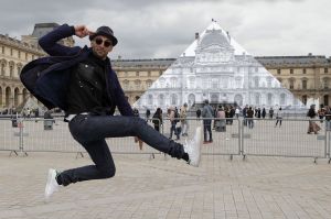 Street artist JR poses in front of the Louvre Pyramid in Paris on Tuesday. His latest project is an eye-tricking installation at the Louvre Museum that makes it seem as if the huge glass pyramid at the heart of the courtyard has disappeared.