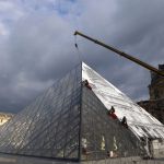 Technicians paste a giant picture on the glass Louvre Pyramid in Paris on Monday.