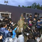 Japan Ground Self-Defense Force Sgt. Maj. Yuichi Kakegawa (center) speaks to the media outside the longhouse-style hut building where 7-year-old Japanese boy Yamato Tanooka was found safe nearly a week after he was abandoned in a forest by his parents.